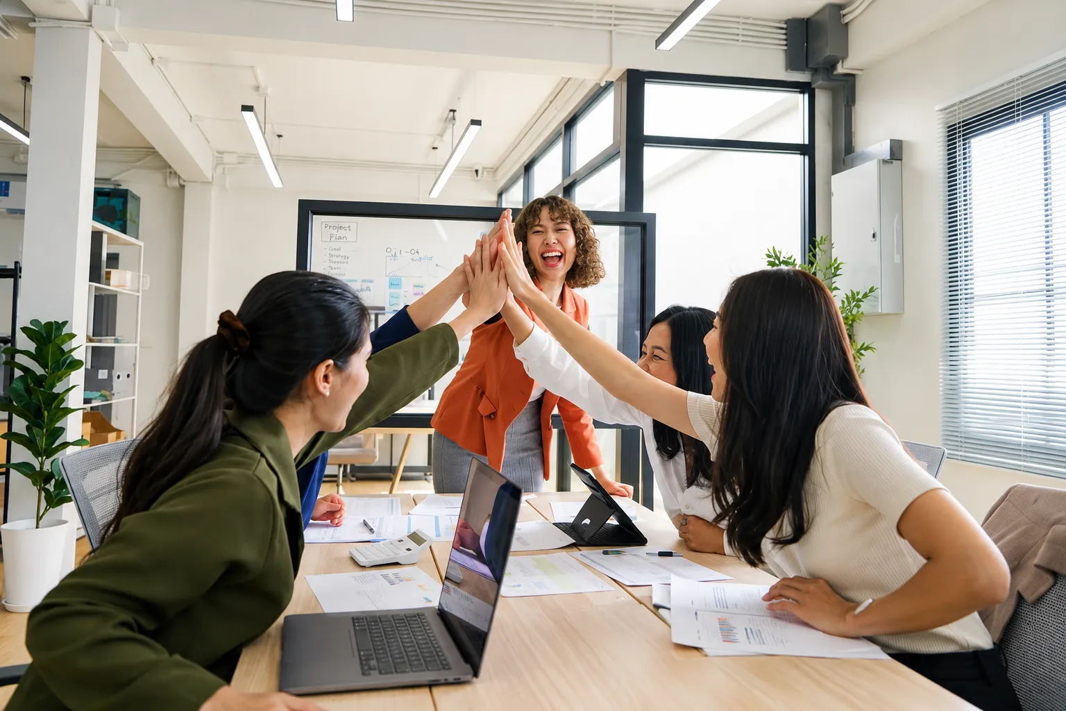 Colleagues sharing a high five around an office table