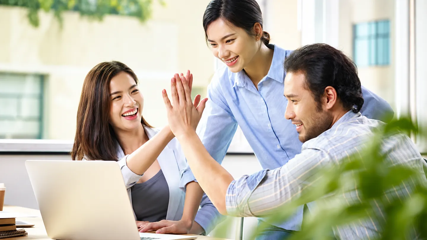 Colleagues giving each other a high five at a shared desk
